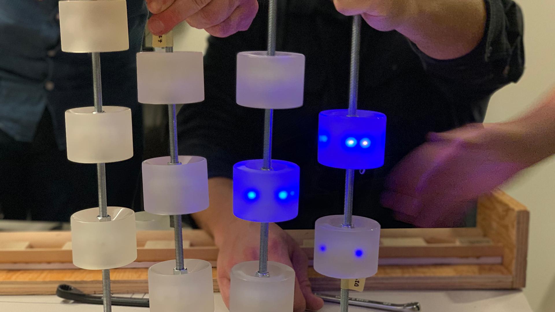 Hands assembling motion-activated skateboard wheels that glow blue with movement.