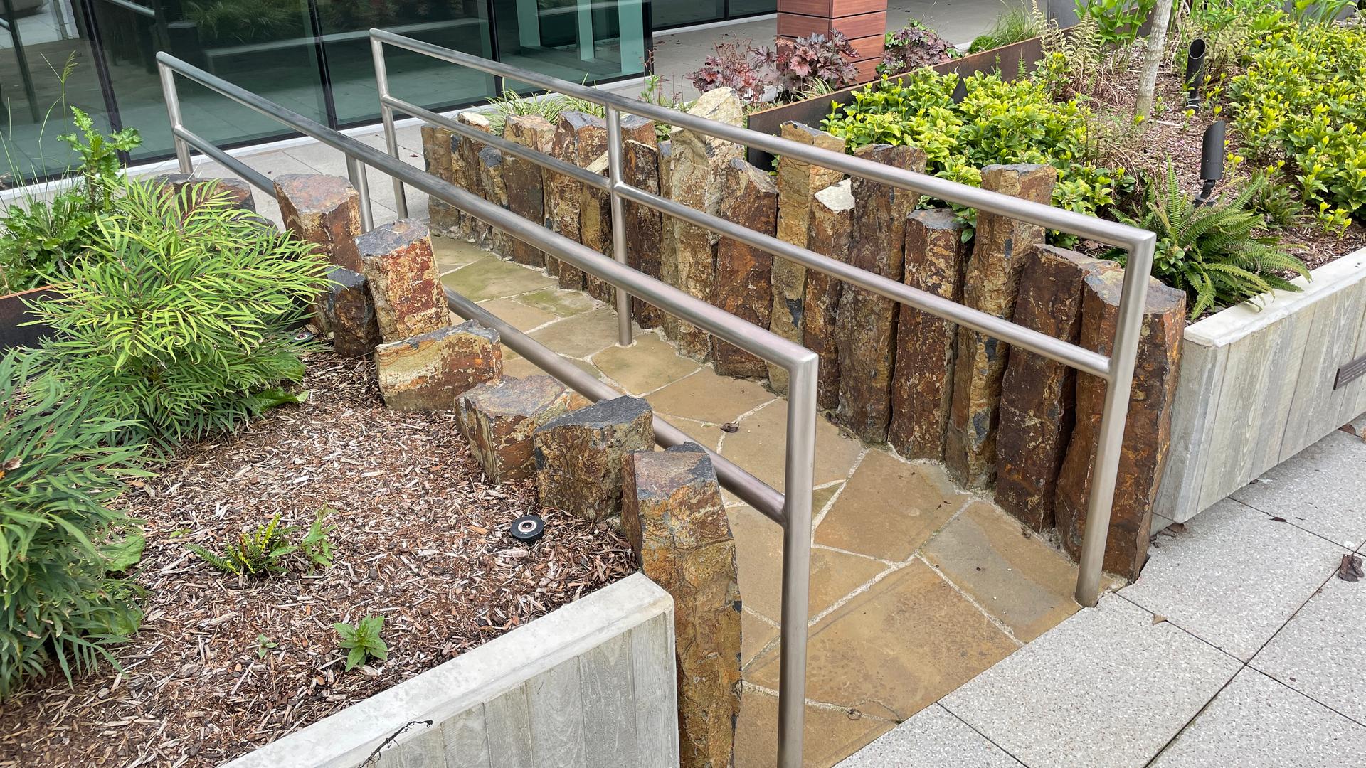 Stone ramp with handrails surrounded by plantings in the therapeutic garden.