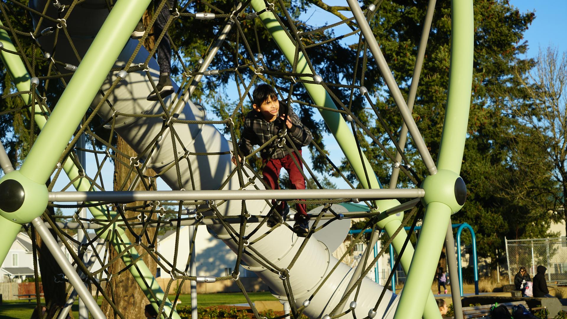Child climbing on a tall play structure at Mill Park.