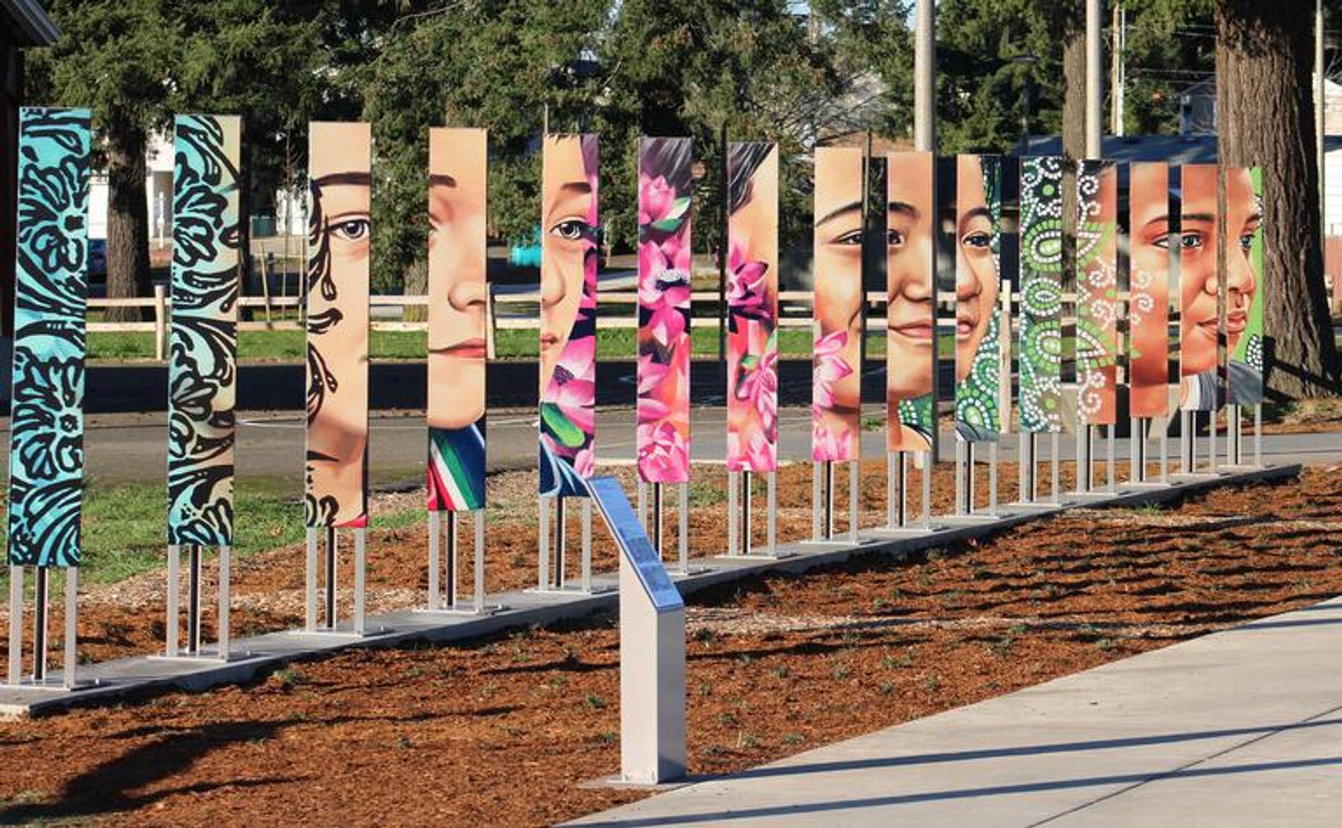 Colorful outdoor artwork with painted faces on vertical panels at Mill Park.