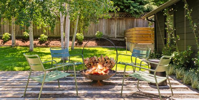 Chairs around a fire pit on the backyard patio at a private Portland residence.