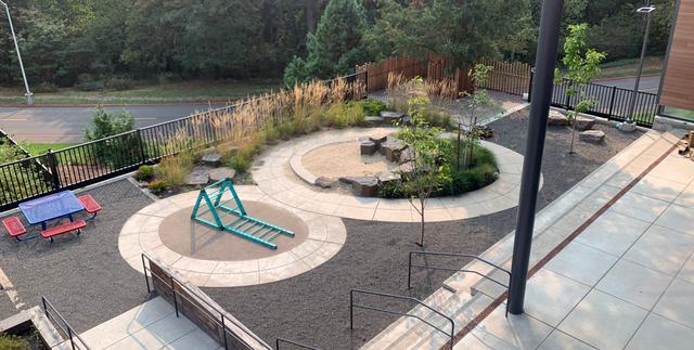 Outdoor play area at PCC Child Development Center with a picnic table, sand play circle, and climbing structure.